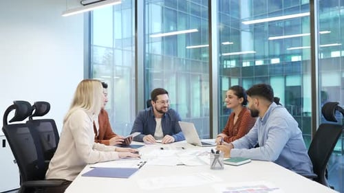 Businesswomen shaking hands after deal at group meeting sitting in office boardroom. Business people