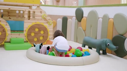 Little Girl Plays in Indoor Ball Pit Playground