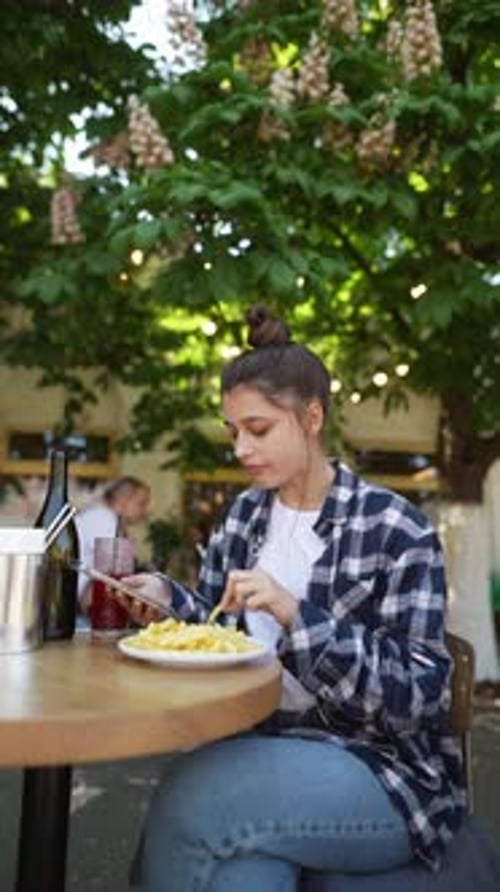 Amidst the Ambiance of a Summer Café Terrace a Gorgeous Girl is Relishing French Fries
