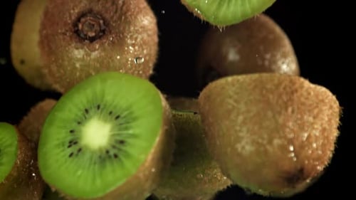 Fresh Kiwi Fruit Pieces Floating on Black Background