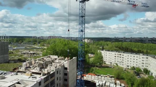 a Crane is on Top of a Building Under Construction in a City Area with Trees and Buildings in the