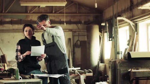 Man And Woman Workers In The Carpentry Workshop.