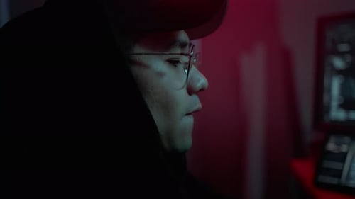 Asiatischer Cyberkrimineller in Hood arbeitet im Dark Room am PC