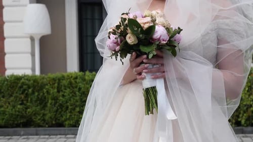 Bride Holding Bouquet Wearing Wedding Dress and Veil