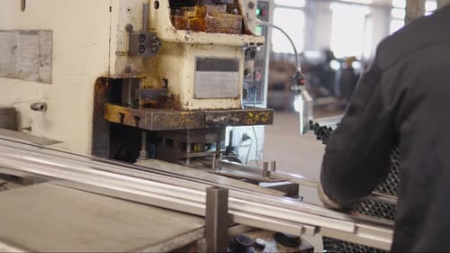 Factory Worker in Protective Gear Operating Metal Punching Machine Processing Aluminum Tubes in an