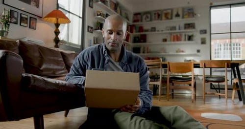 Man Sitting on Floor with Box Using Phone