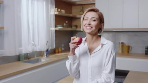 Smiling woman holding and looking at an apple