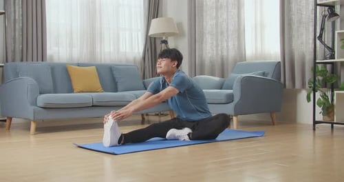 Young Adult Man Stretching Hamstrings on Exercise Mat