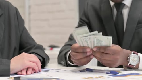 Close up of Businessman Giving Money to Female Business Partner