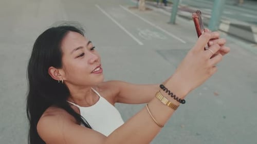 Young woman taking selfie on mobile phone while standing on modern city background