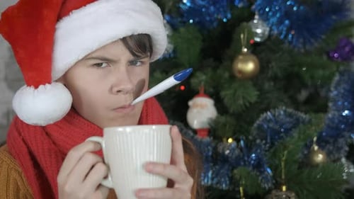 Teen Sick at Christmas Time Holds Thermometer