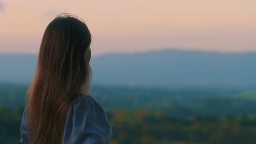 Woman Looks at Sunset Landscape in Golden Light