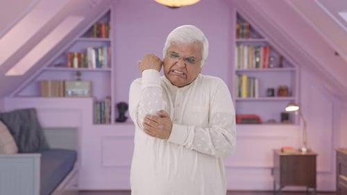 Senior Adult Massaging Sore Elbow in Bedroom