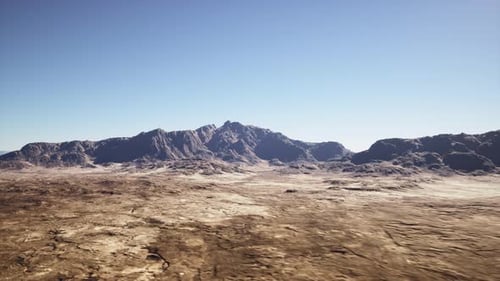 Expansive Dry Terrain with Distant Rocky Ridges and Clear Heavens