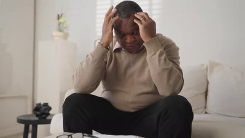 Man Sitting on Couch with Money and Papers