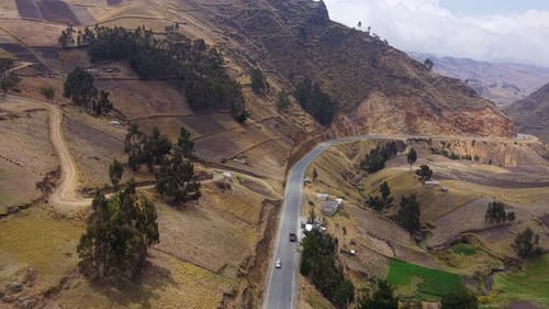 Serpentine Roadway Curving Through Lush Valley Vehicles Winding Along Mountain Asphalt with Andean