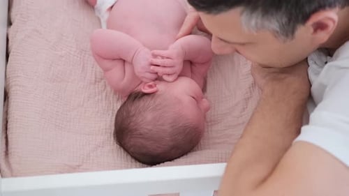 Infant Lying in Crib with Parent Looking On