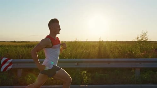 Strong Man Wearing Sportswear Running Quickly in Road at Sunset