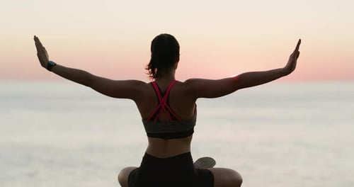 Woman Meditating by the Ocean at Sunrise
