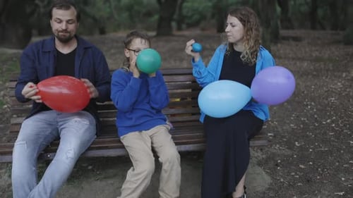 Family Inflating Balloons in Park