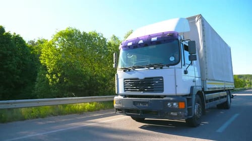 Big Truck with Cargo Trailer Driving on Highway and Transporting Goods at Sunny Day White Lorry