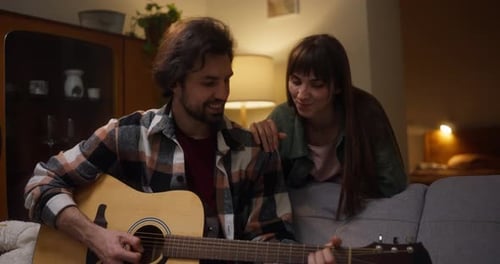 Loving Couple Man Plays Guitar For Woman At Home