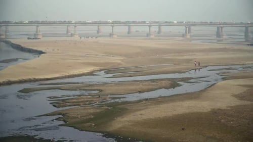 Fast pan to the empty river with its standing water, And a bridge, with traffic going on, Trees, Ele