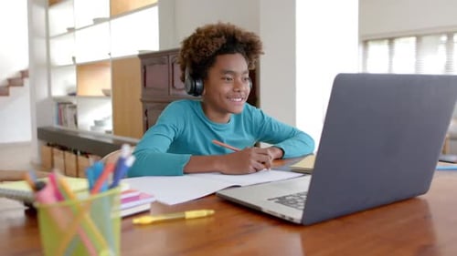 Boy Learning with Laptop and Notebook at Home