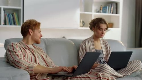 Couple Relaxing on Couch with Laptops Indoors