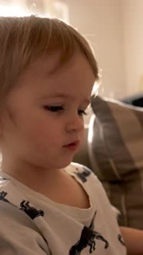 Vertical of Little Boy Playing With Stuffed Animal on Couch