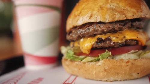 Großer Burger mit Rinderschnitzel, Tomaten und Gurken mit geschmolzenem Käse, Nahaufnahme