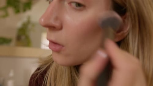 Woman Applies Makeup with Brush Indoors