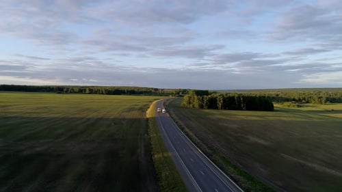 Luftaufnahme von Lastwagen und Autos, die auf einer Intercity-Straße zwischen grünen Feldern im schönen