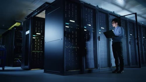 In Data Center: Male IT Technician Running Maintenance Programme on a Laptop, Controls Operational