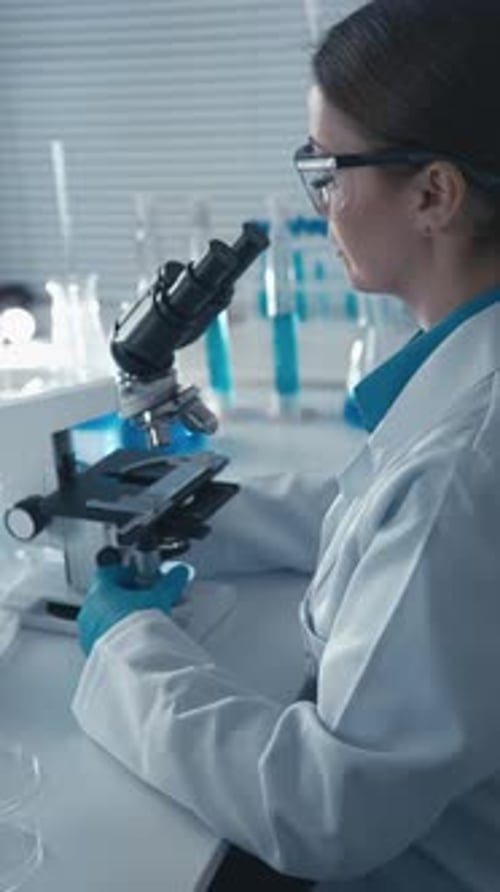 Female Scientist Works with Microscope in Lab