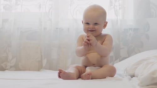 Happy Baby Clapping Hands on Bed Indoors