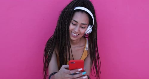 Smiling woman with headphones uses smartphone app