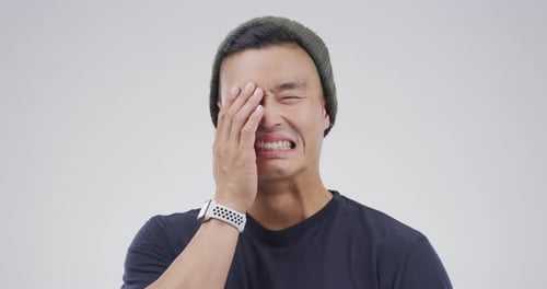 A young man crying against a grey background