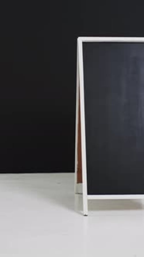 Vídeo vertical del letrero de pizarra sobre soporte blanco con espacio para copiar sobre fondo negro