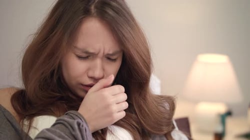 Portrait of Ill Woman at Home. Young Woman Coughing in Bedroom. Close