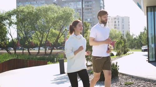 Active Young Caucasian People Running Outdoors in Urban City on Summer Day Athletic Man and Smiling