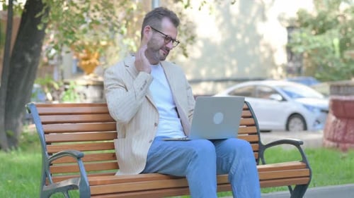 Man Working on Laptop Outside on Bench
