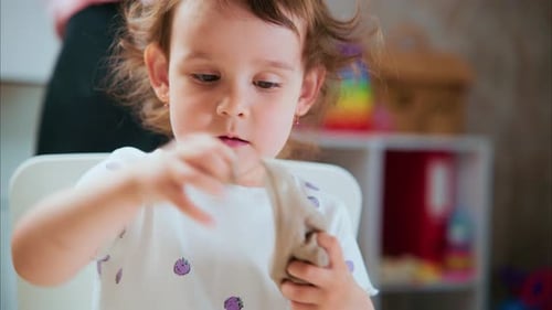 Young Girl Playfully Molding Clay Indoors in Close-Up