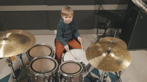 Young Boy Happily Playing Drums in Music Studio