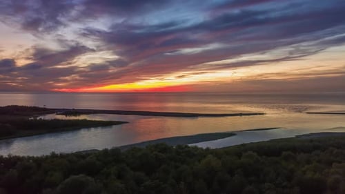 Drone hyperlapse of seascape and coastline against colourful sunset cloudscape