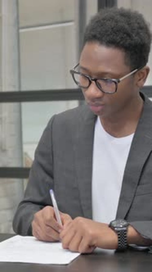 Vertical, Young African Man Working on Documents in Office