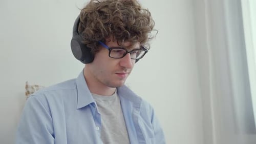Young Man with Headphones Using Laptop at Home