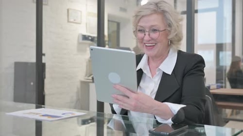 Mature Woman Video Conferencing with Tablet in Office