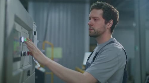 Technician Operating Control Panel of Automated Machinery in Printing Factory