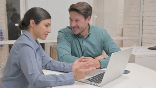 Adults Collaborating on Laptop in Bright Workplace